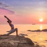 Frau am Strand, die Yoga macht